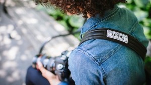 Black leather camera strap from ONA slung over woman's shoulder